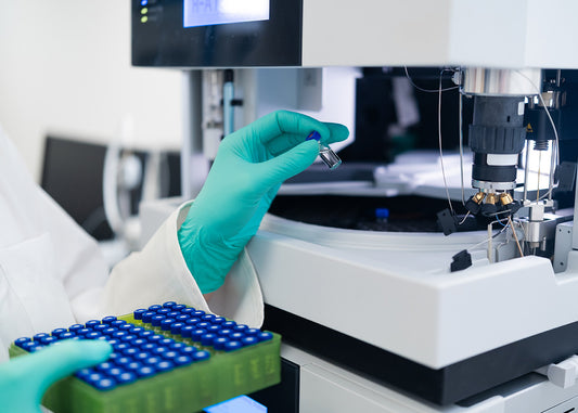Laboratory setting with a scientist handling a sample using a microscope.